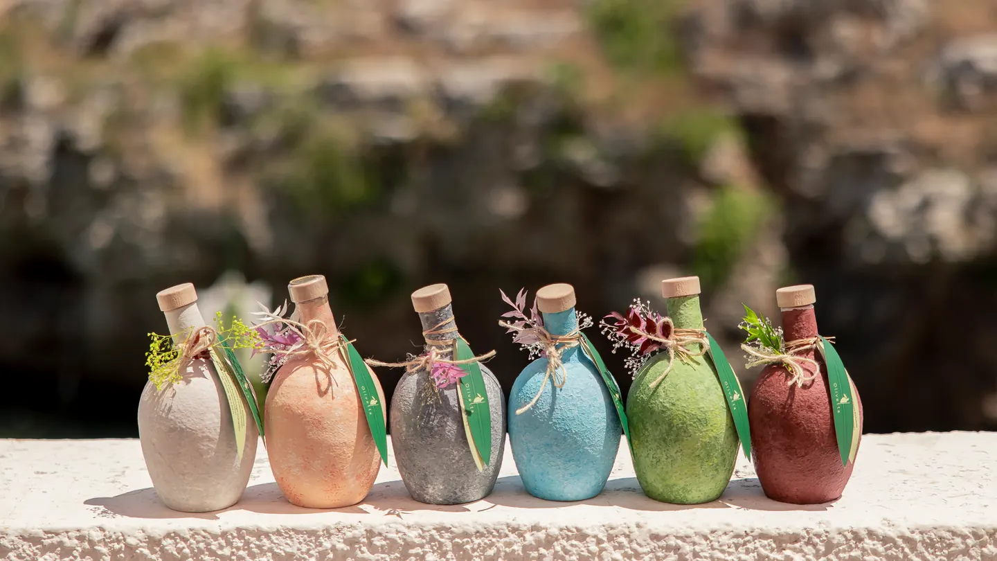 Šest barevných keramických lahví Oliva Ceramica na kamenné zídce